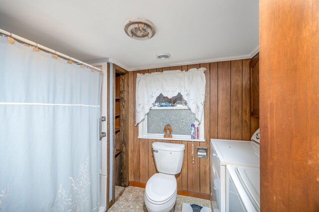 full bathroom with toilet, wood walls, and separate washer and dryer