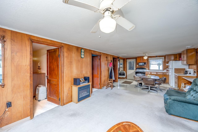 living room with light colored carpet, wood walls, and a ceiling fan