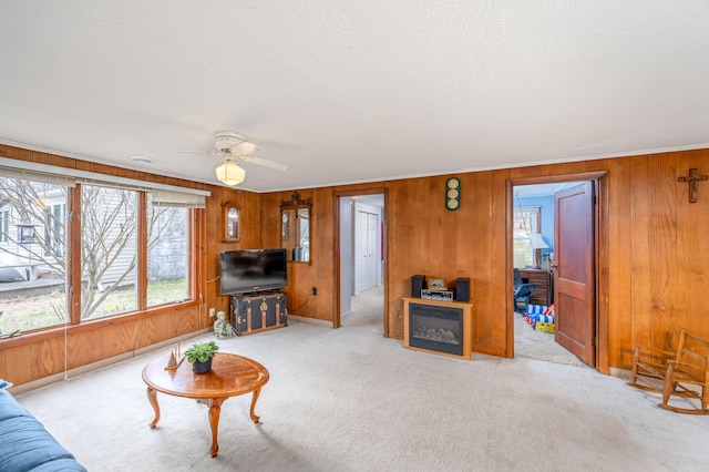 carpeted living room featuring a textured ceiling, wood walls, and a ceiling fan