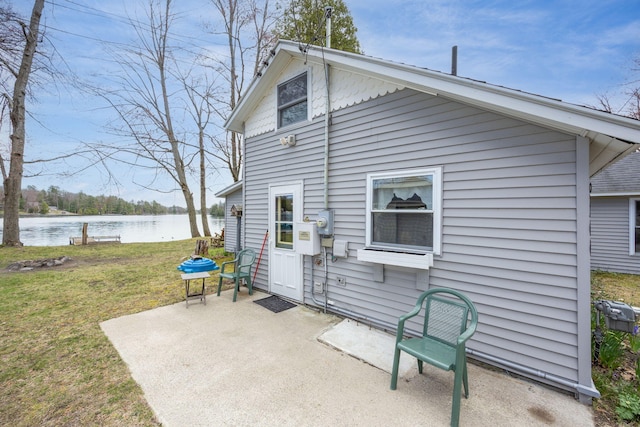 rear view of property featuring a lawn, a water view, and a patio