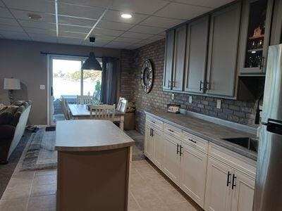 935 Stony Lake Ct, Oxford, MI 48371 - kitchen featuring light tile patterned floors, open floor plan, a drop ceiling, and a kitchen island