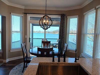 935 Stony Lake Ct, Oxford, MI 48371 - dining area with dark wood-style flooring, a notable chandelier, a water view, baseboards, and ornamental molding