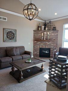 935 Stony Lake Ct, Oxford, MI 48371 - carpeted living room with lofted ceiling, crown molding, a brick fireplace, and visible vents