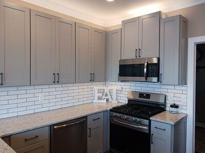 935 Stony Lake Ct, Oxford, MI 48371 - kitchen with backsplash, light stone countertops, gray cabinets, and stainless steel appliances