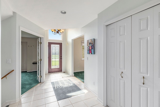 foyer with baseboards, a chandelier, and light tile patterned floors