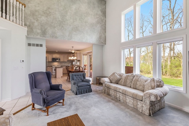 living room with plenty of natural light, baseboards, visible vents, and a towering ceiling