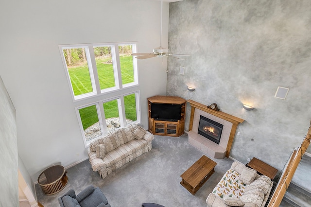 carpeted living area with plenty of natural light, a towering ceiling, and a fireplace