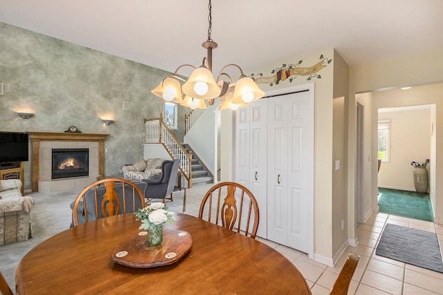 dining room with a fireplace, baseboards, a chandelier, stairs, and light tile patterned flooring