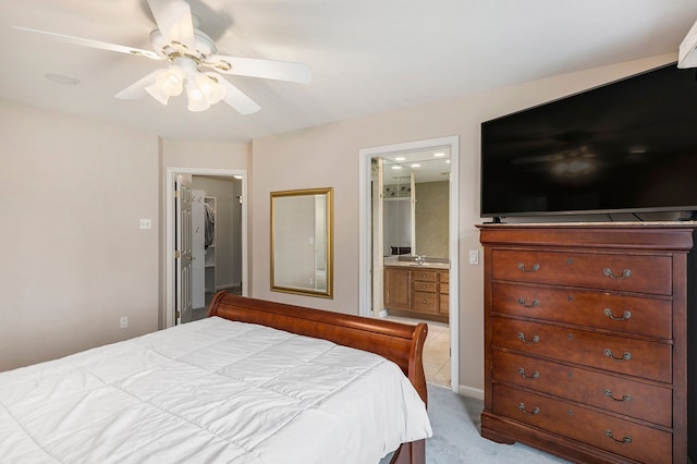 bedroom featuring ceiling fan, ensuite bath, and light colored carpet