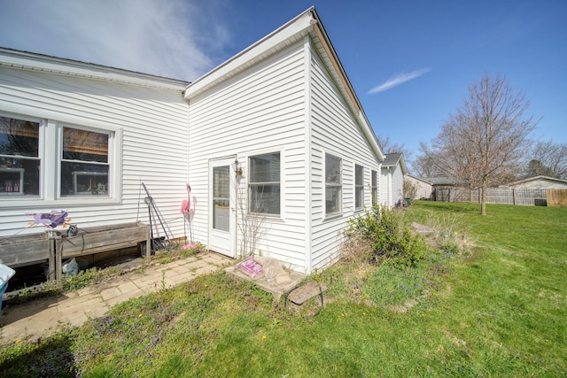 view of side of home with a lawn and fence