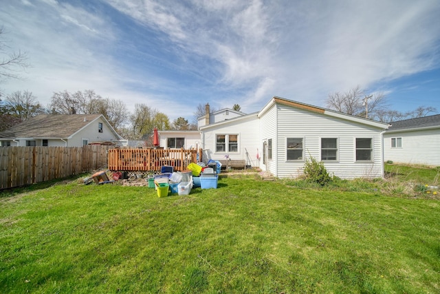rear view of property with fence, a yard, and a deck