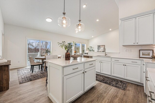 kitchen with light countertops, light wood-style floors, tasteful backsplash, and a sink