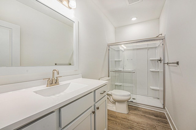 bathroom with recessed lighting, a shower stall, wood finished floors, toilet, and vanity