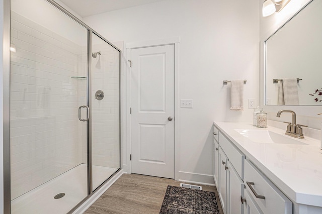 bathroom featuring a shower stall, wood finished floors, vanity, baseboards, and visible vents