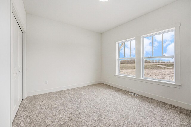 unfurnished bedroom with baseboards, light carpet, visible vents, and a closet