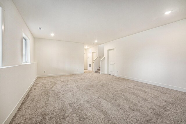 spare room with light colored carpet, baseboards, and recessed lighting