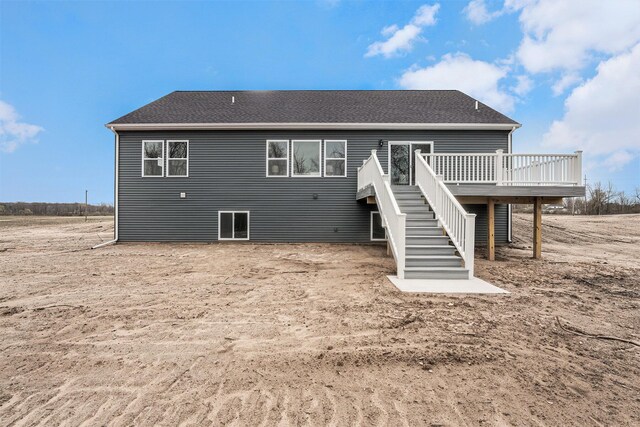 rear view of house with a deck, stairs, and a shingled roof