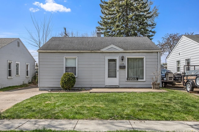 bungalow-style home featuring a shingled roof and a front yard