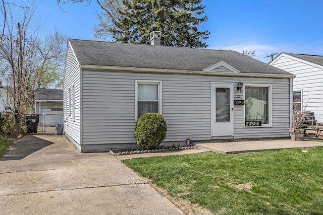 bungalow-style house featuring a chimney, a gate, fence, a front lawn, and roof with shingles