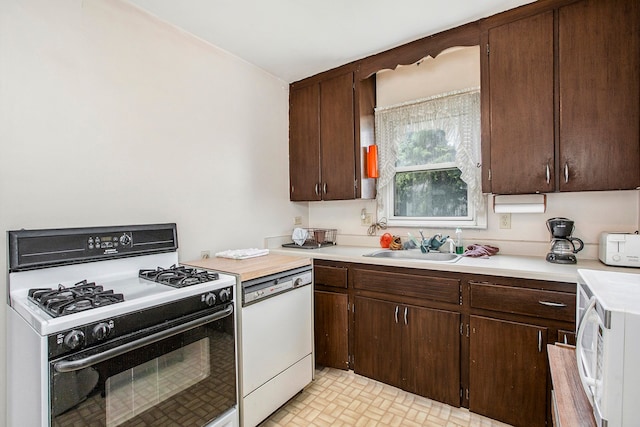kitchen with a toaster, light countertops, dark brown cabinets, a sink, and white appliances