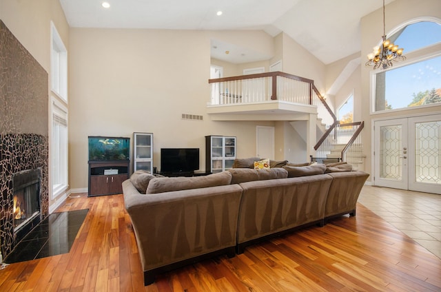 28909 Hidden Trl, Farmington Hills, MI 48331 - living area with high vaulted ceiling, stairway, a tile fireplace, hardwood / wood-style flooring, and a chandelier
