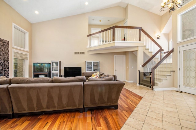 28909 Hidden Trl, Farmington Hills, MI 48331 - living room featuring stairway, high vaulted ceiling, a chandelier, healthy amount of natural light, and wood finished floors