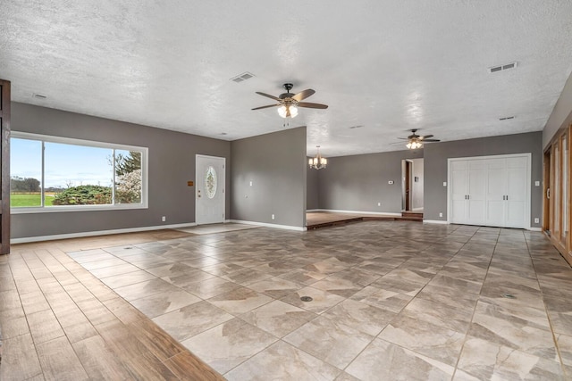 unfurnished living room with baseboards, a textured ceiling, visible vents, and ceiling fan with notable chandelier