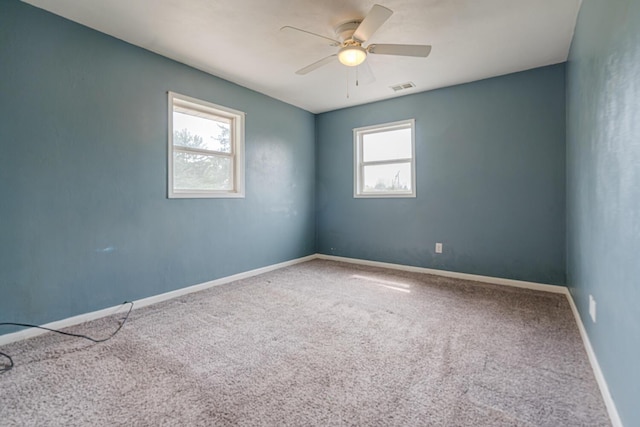 carpeted empty room with baseboards, visible vents, and ceiling fan