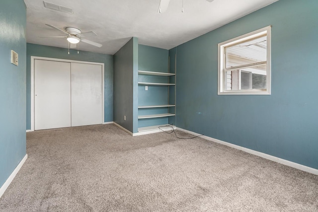 unfurnished bedroom featuring a closet, ceiling fan, carpet floors, baseboards, and visible vents