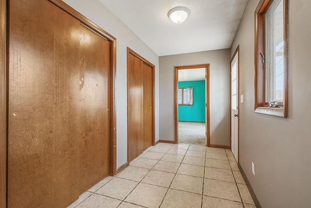 hall featuring baseboards and light tile patterned floors