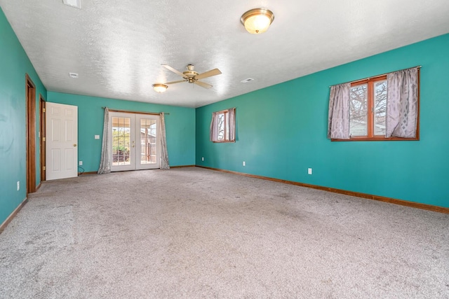 carpeted spare room with baseboards, a ceiling fan, french doors, and a textured ceiling