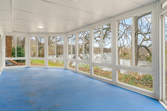 unfurnished sunroom with finished concrete floors and a water view