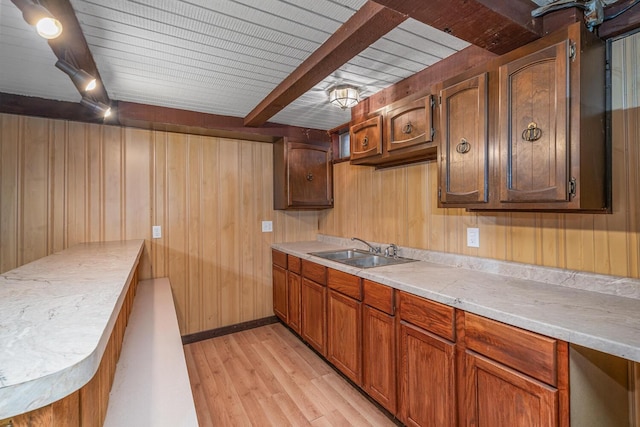 kitchen featuring wood walls, a sink, light wood finished floors, and light countertops