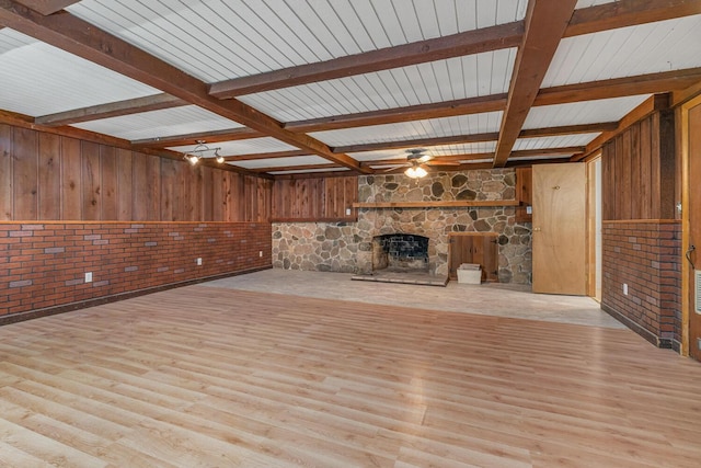 unfurnished living room featuring a ceiling fan, wood finished floors, beamed ceiling, and a fireplace