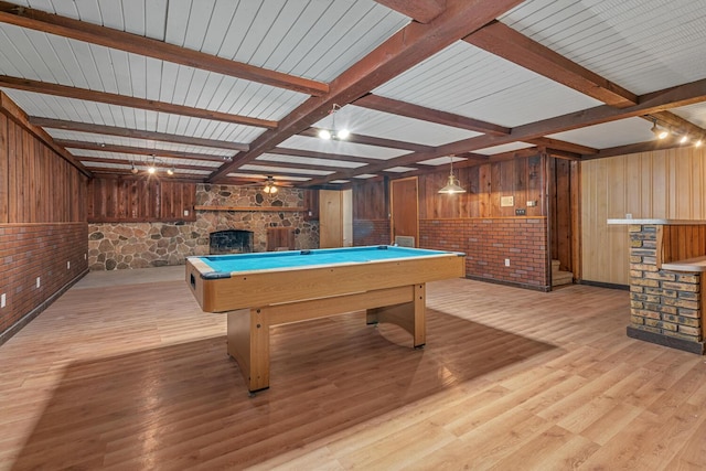 playroom featuring beam ceiling, a stone fireplace, pool table, and light wood-style flooring