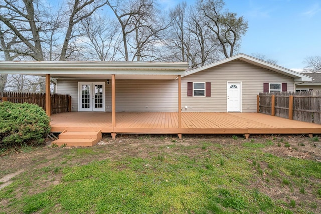 rear view of house featuring a wooden deck, fence, and french doors