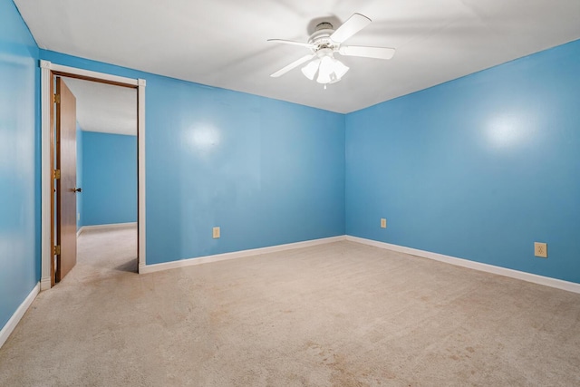 carpeted spare room with a ceiling fan and baseboards
