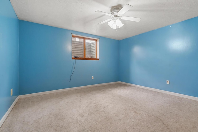 empty room featuring a textured ceiling, carpet flooring, baseboards, and ceiling fan