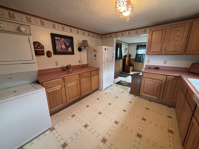 1026 Lakeview Dr, Brooklyn, MI 49230 - kitchen with brown cabinets, freestanding refrigerator, stacked washing maching and dryer, and a textured ceiling