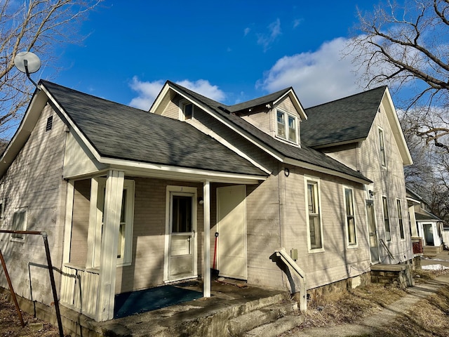 back of house with a porch and a shingled roof