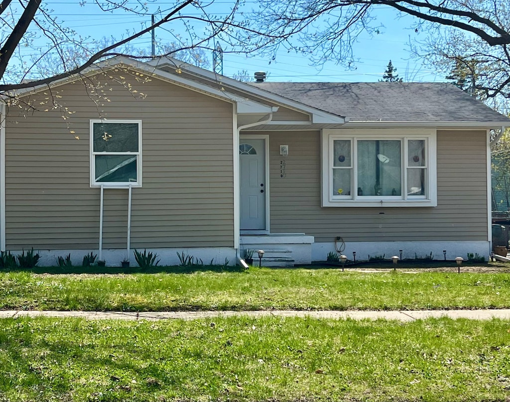 view of front of property with a front yard and roof with shingles