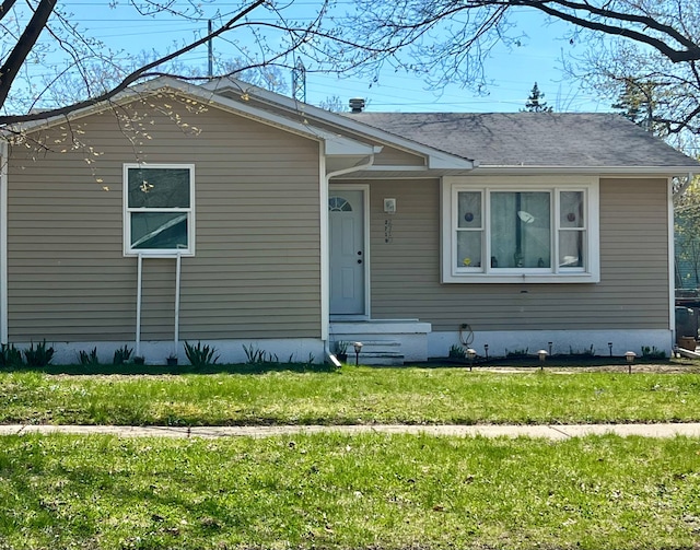 view of front of property with a front yard and roof with shingles