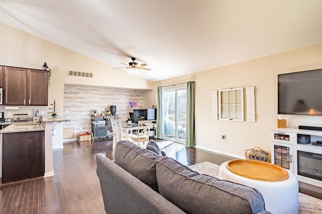 1242 Bay, Holly, MI 48442 - living room with dark wood-style flooring, ceiling fan, a wood stove, baseboards, and visible vents