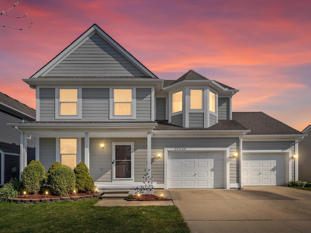 traditional-style home with an attached garage, driveway, a shingled roof, and covered porch