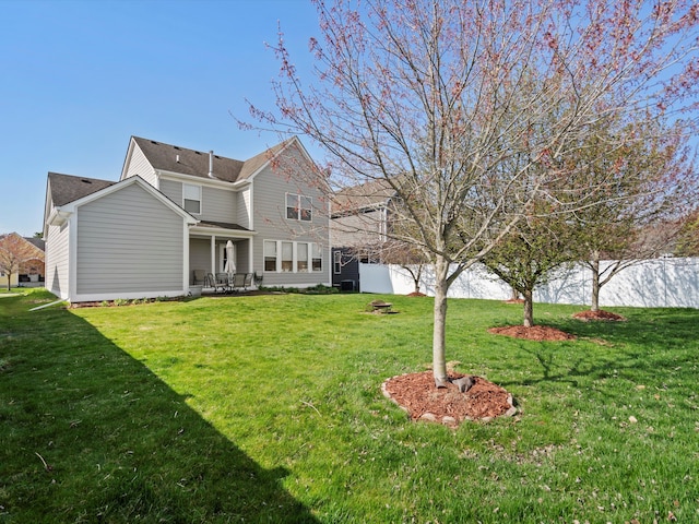 rear view of house with a patio area, a lawn, and fence
