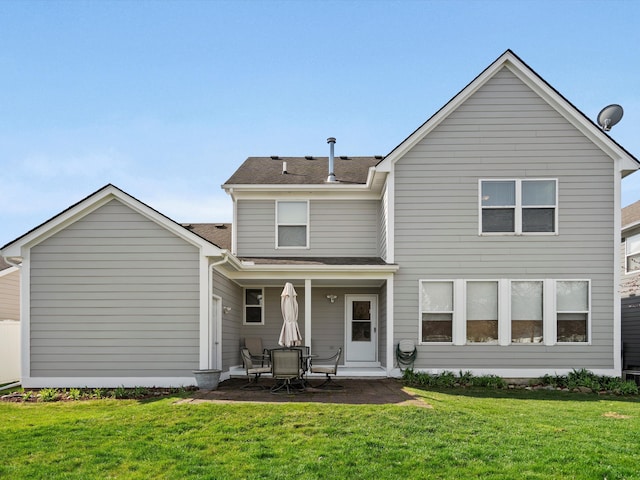 back of house featuring a lawn, roof with shingles, and a patio area