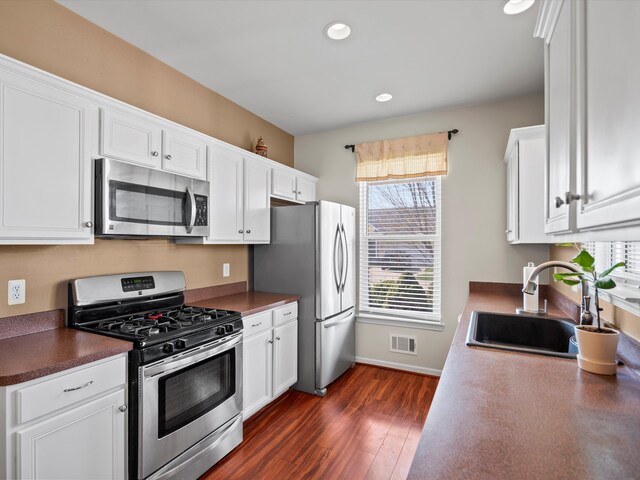 kitchen featuring white cabinets, stainless steel appliances, a sink, and dark wood finished floors