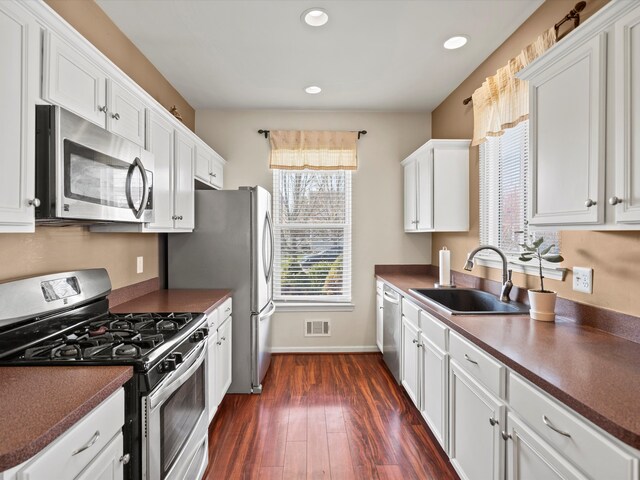 kitchen with white cabinets, dark countertops, visible vents, and stainless steel appliances