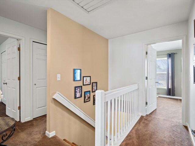 hallway featuring carpet floors, an upstairs landing, and baseboards