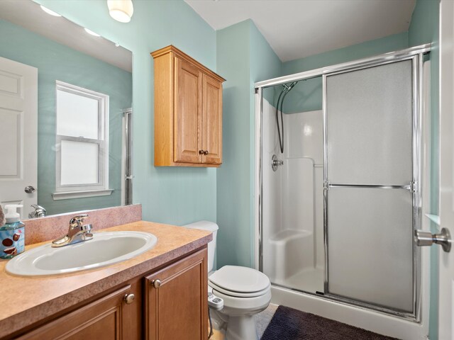 bathroom featuring toilet, vanity, and a stall shower